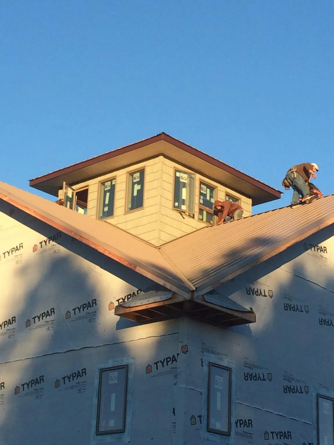 Roofers working around a rooftop cupola on a new metal roof at sunset — Roof Waterproofing in Silver Lake by Roofing Brothers